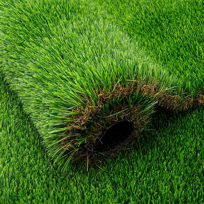 Close-up of artificial grass blades and brown thatch around a rolled edge.